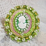 Bague Anisse brod&eacute;e d&rsquo;un cabochon r&eacute;sine repr&eacute;sentant une femme et des roses, orn&eacute;e de rocailles Vert Anis, Rose, Jaune Nacr&eacute; et Ivoire. Elle est finie avec des toupies et perles sur bague r&eacute;glable 